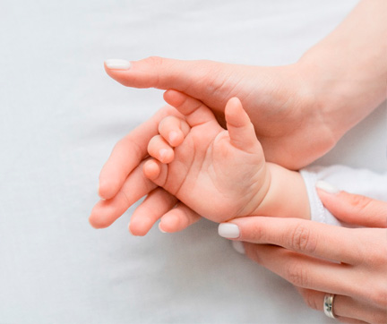 Una mande un bebé sobre la mano de su madre.
