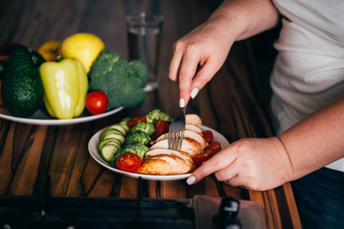 Persona comiendo un plato con alimentos ricos en proteínas.