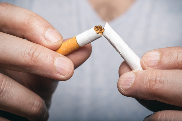Persona rompiendo un cigarrillo para limpiar sus pulmones de tabaco.