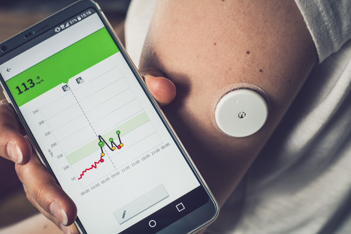 Persona midiendo sus niveles de glucosa con un el móvil para identificar un posible pico de glucosa.