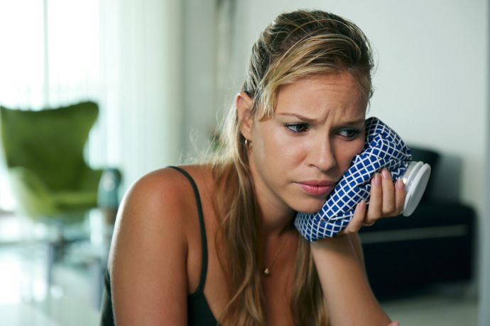 Persona aplicando frío en su mandíbula, un remedio para el dolor de muelas.