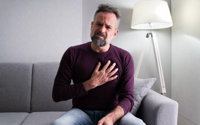 Hombre quejándose de dolor por no saber cómo bajar el colesterol de forma natural.