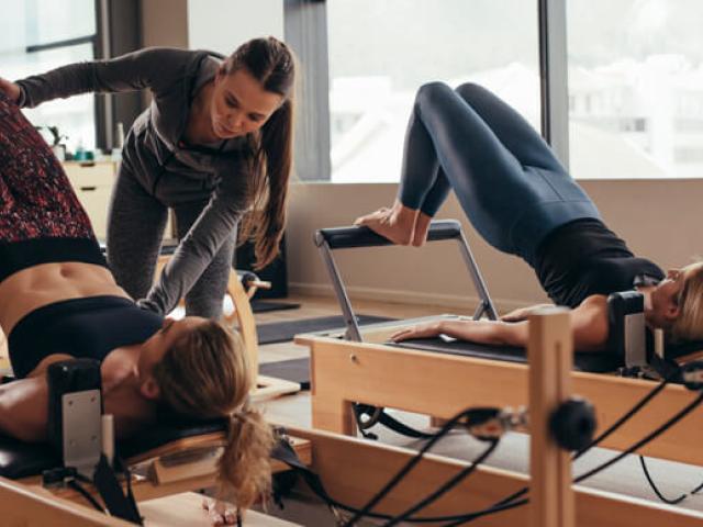 Mujeres haciendo pilates en máquinas para disfrutar de sus beneficios.