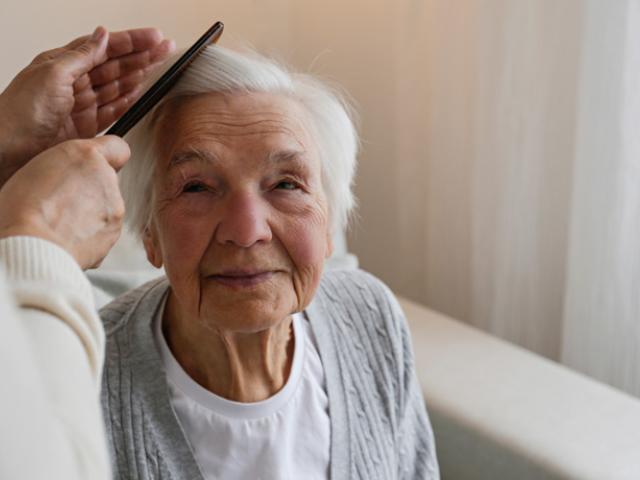 Cuidadora peinando a una mujer mayor.
