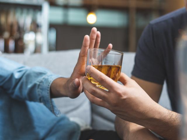 Persona rechazando bebida porque le sienta mal el alcohol.